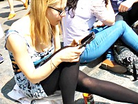 Real amateur girl is sitting on the stairs in the city center. Paying no attention on the crowd around she is exposing black pantyhose up skirt legs